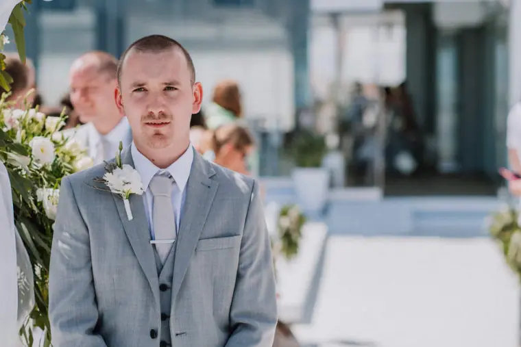 Mike waiting at the front in a grey suit as the ceremony begins