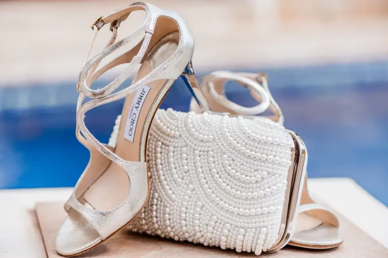 Silver strappy heels and a pearl-beaded clutch bag by the pool