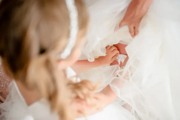 Flower girl fluffing out the bride's tulle skirt