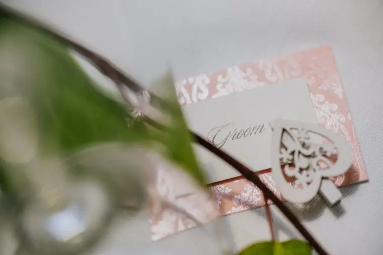 Groom's place card with a wooden heart decoration among ivy