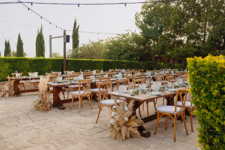 Reception tables set under festoon lights among cypresses and hedges