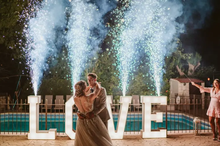 Couple's first dance by the pool with cold-spark fountains and giant light-up LOVE letters