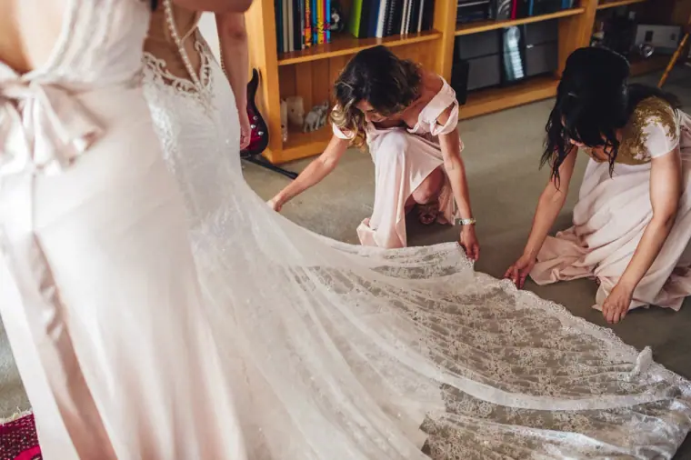 Bridesmaids arranging the long lace train of Ruby's dress