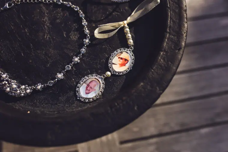 Pearl bracelet with photo memorial charms on a wooden surface