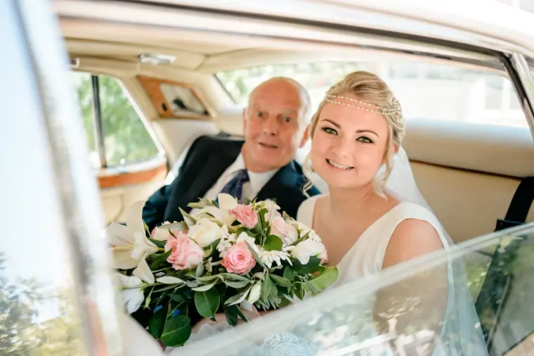 Francesca smiling beside her father in the back of the wedding car