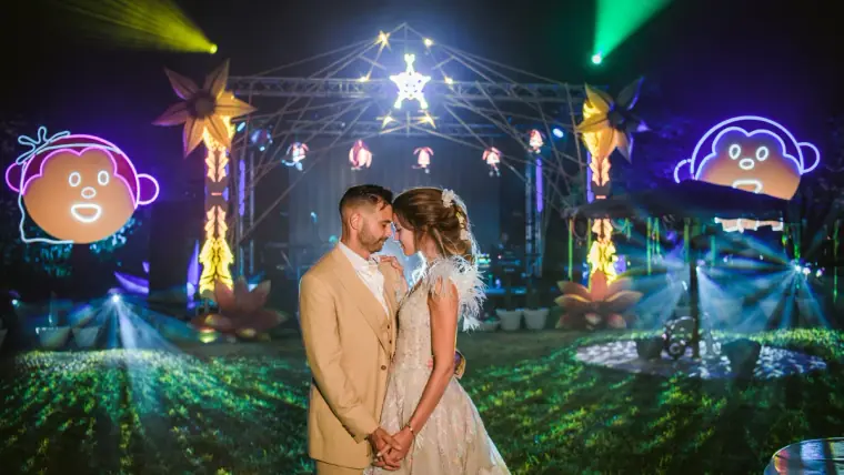 Kenton and Hassiba touching foreheads before a festival stage with lights and lasers