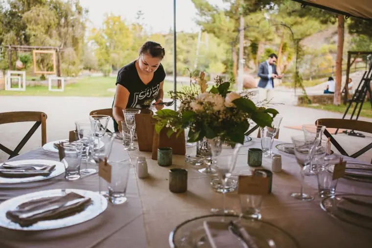 Florist arranging white flowers and candles on a round reception table