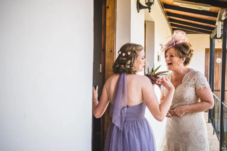 Bridesmaid in lilac with a guest in lace and a fascinator on the veranda