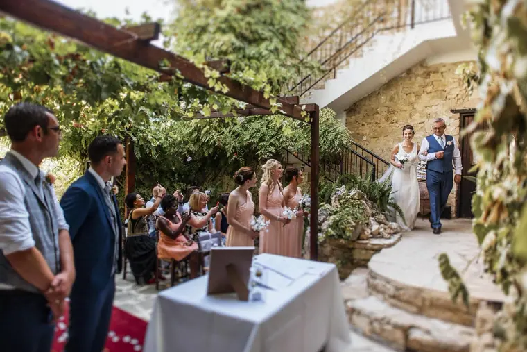 Bride arriving down the steps to the courtyard ceremony as guests wait under the pergola
