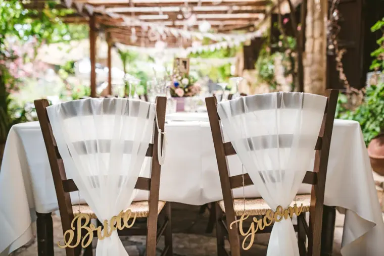 Bride and Groom signs on chairs draped with white tulle at the top table