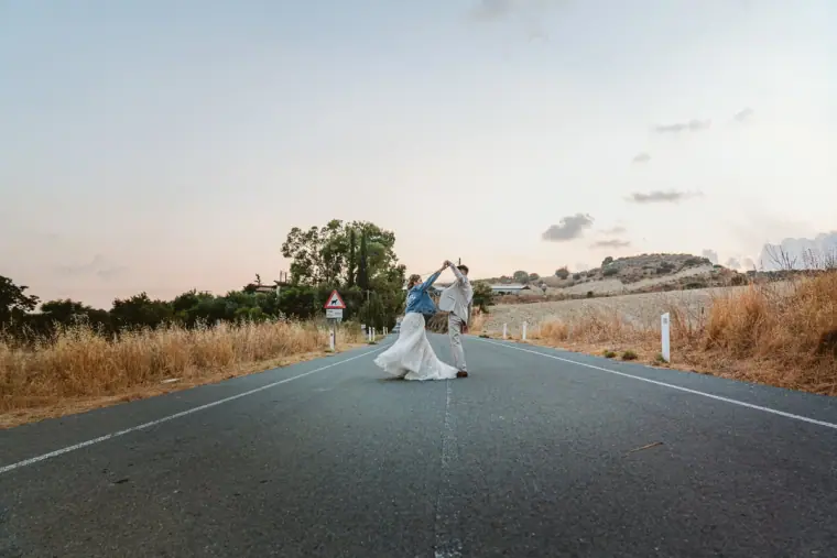 Groom lifting the bride on an empty country road at dusk