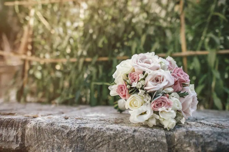 Pink and white rose bouquet resting on a stone wall