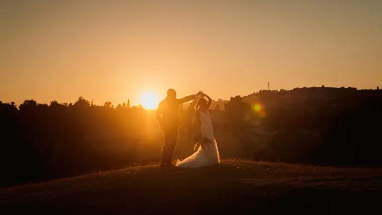 Couple dancing silhouetted against the setting sun over the hills