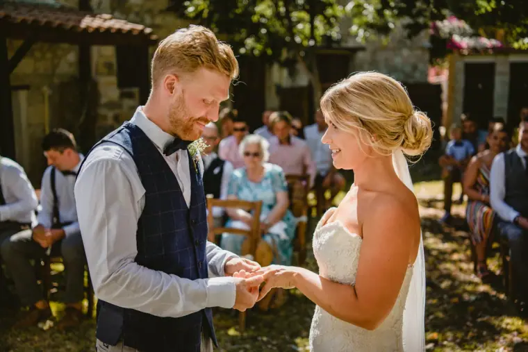 Paul placing the ring on Fiona's finger in the stone courtyard