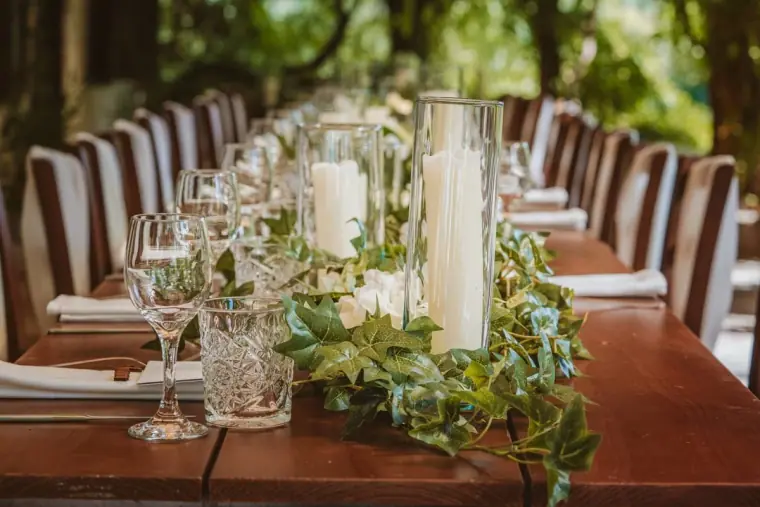 Table set with pillar candles in glass hurricanes, ivy garlands and wine glasses