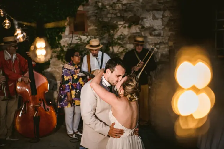Couple kissing on the dance floor as the band plays behind them, glowing lights in front