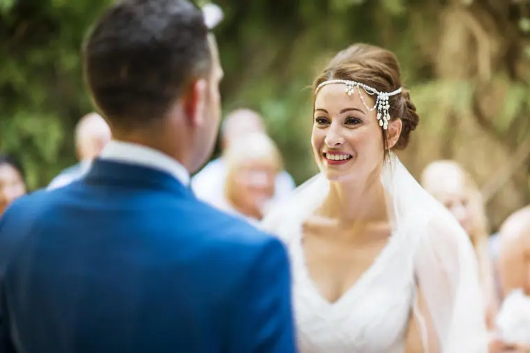 Donna smiling at Byron during their vows in the courtyard