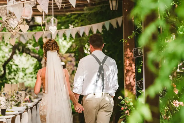 Amie and Graeme walking into a reception decorated with bunting and lanterns
