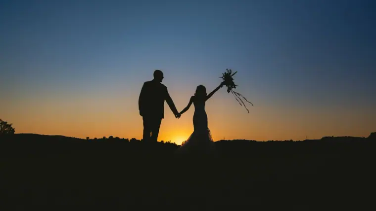 Emily and Chris silhouetted against a sunset sky, bouquet raised high, Minthis, Paphos