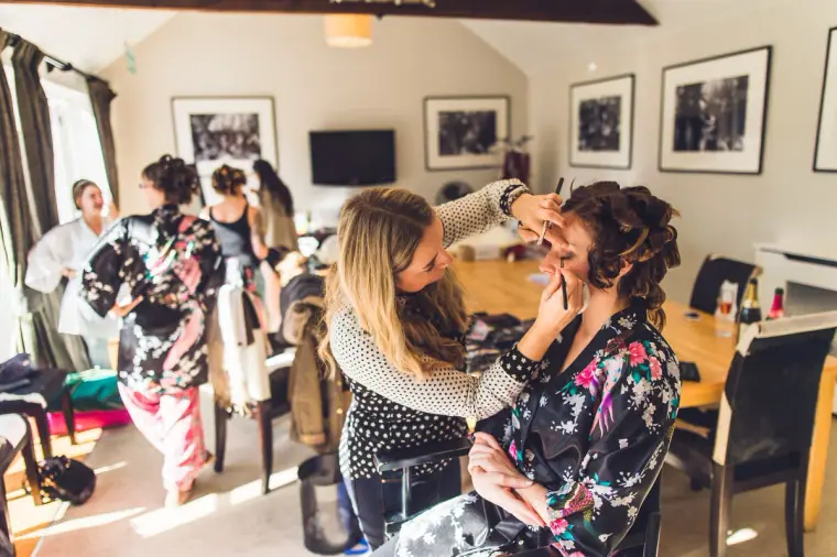 Bridesmaid in a kimono having her make-up applied in the bright bridal suite
