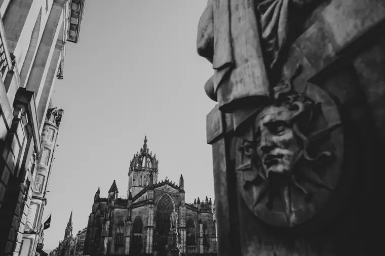 Black-and-white view of St Giles' Cathedral beside a bronze sculpted face, Edinburgh