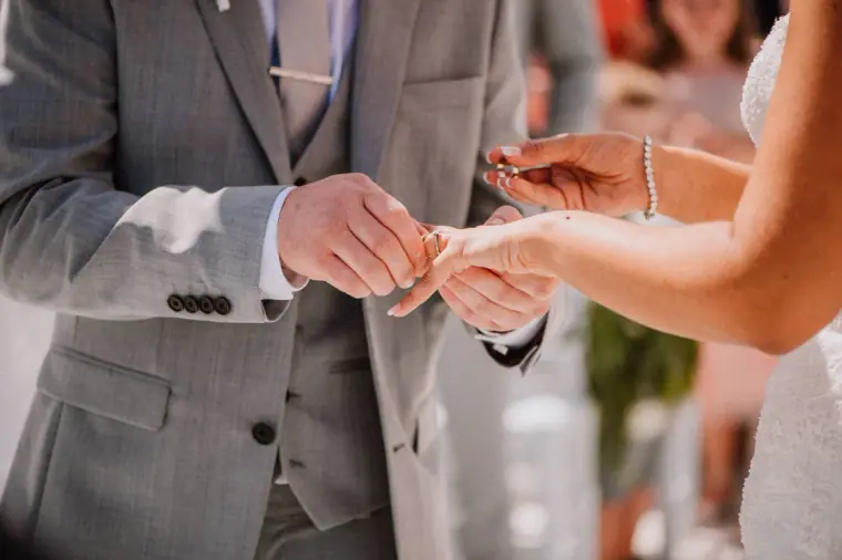 Close-up of the bride placing the ring on the groom's finger