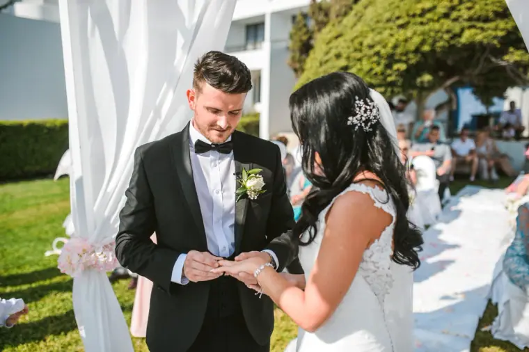 Steven placing the wedding ring on Jaclyn's finger beneath the draped canopy