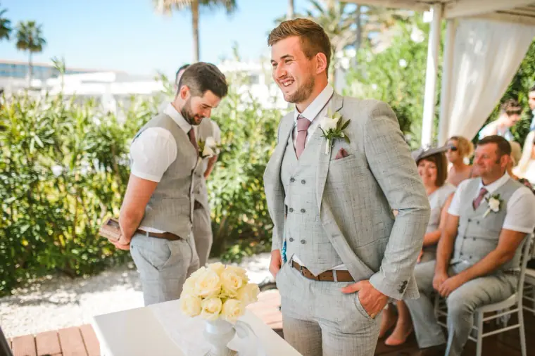 Groom smiling at the front as guests take their seats in the garden, Nissi Beach Resort