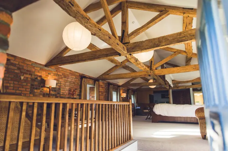 Beamed loft bedroom with exposed brick and paper lanterns at Wasing Park