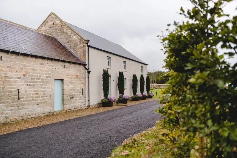 Whitewashed and stone barn buildings beside the driveway at Healey Barn