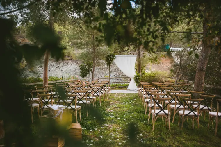 Ceremony chairs in rows facing a draped arch in a wooded garden
