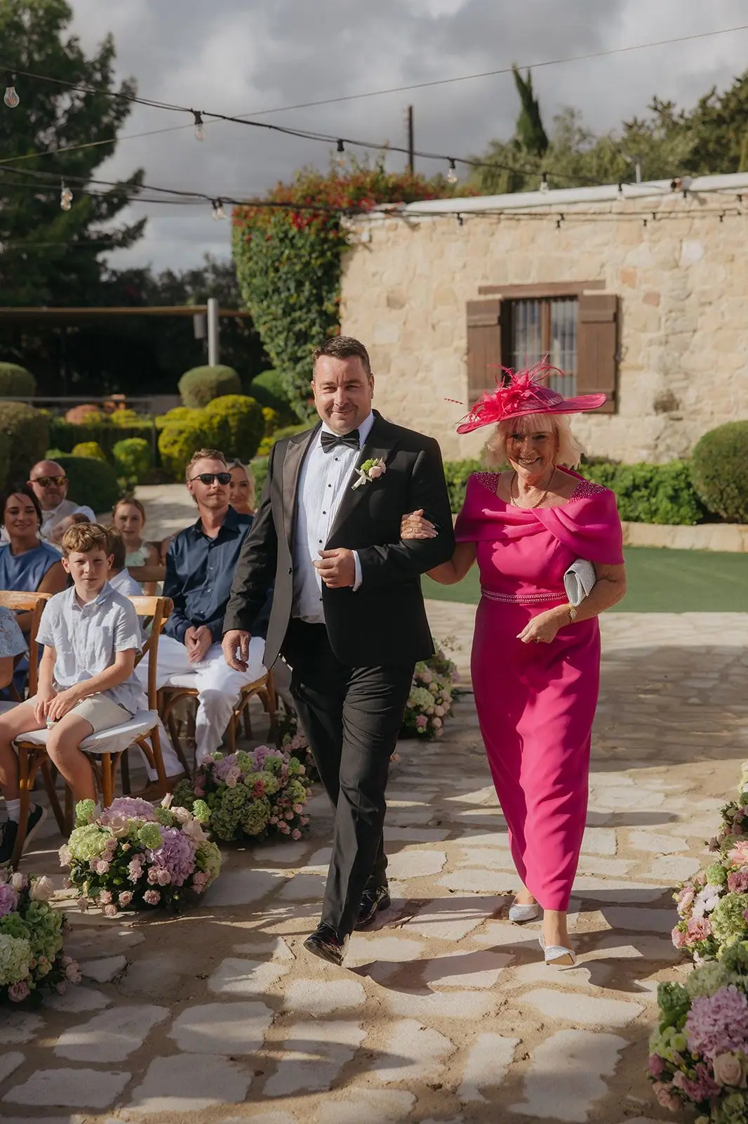 Zoe's mum in fuchsia being walked down the aisle at Liopetro