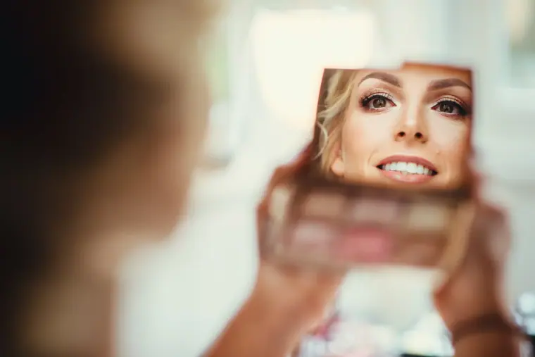 Bride's smile reflected in a handheld compact mirror