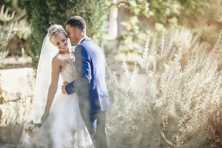 Danny kissing Emmee's forehead among soft garden foliage