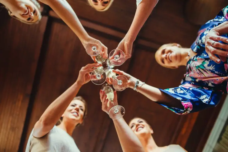 Bridesmaids clinking glasses in a circle, seen from below
