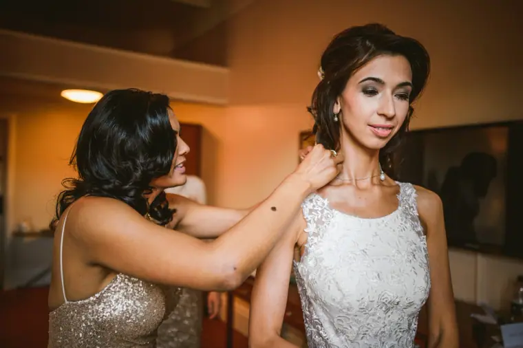 Bridesmaid adjusting the bride's necklace in the hotel suite