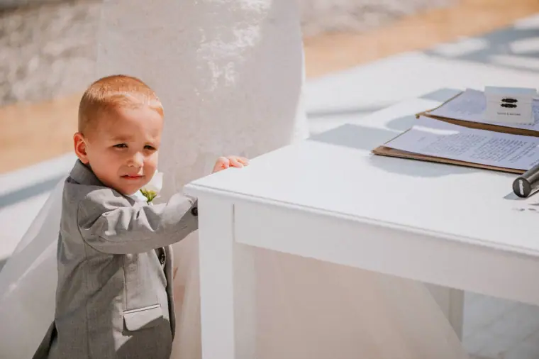 Young pageboy in a grey suit peeking over the signing table