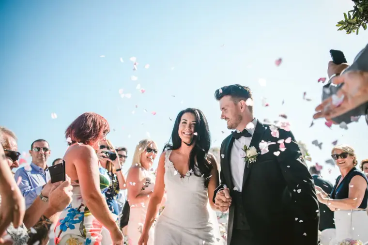 Guests throwing petals over Jaclyn and Steven as they walk back up the aisle