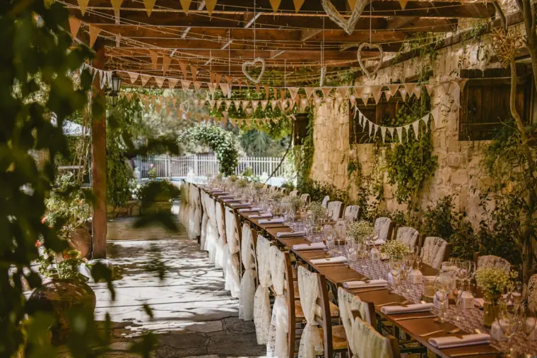 Long reception table under a rustic pergola with bunting and hanging hearts