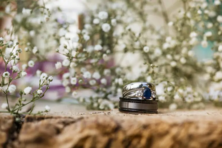 Wedding rings resting on a stone ledge among gypsophila