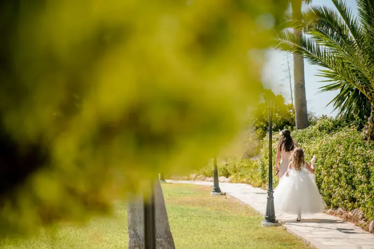 Bride walking along a garden path between palms to the ceremony