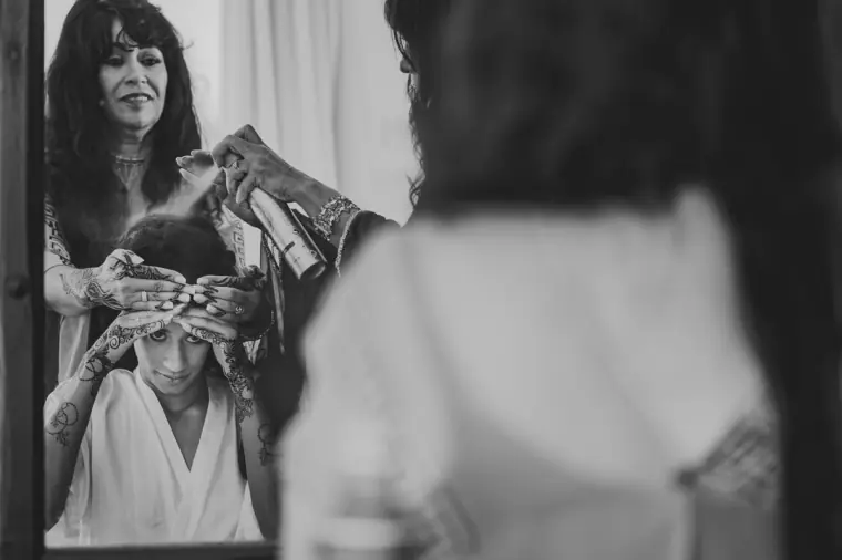 Black-and-white photo of a woman placing a hair piece on the bride's head