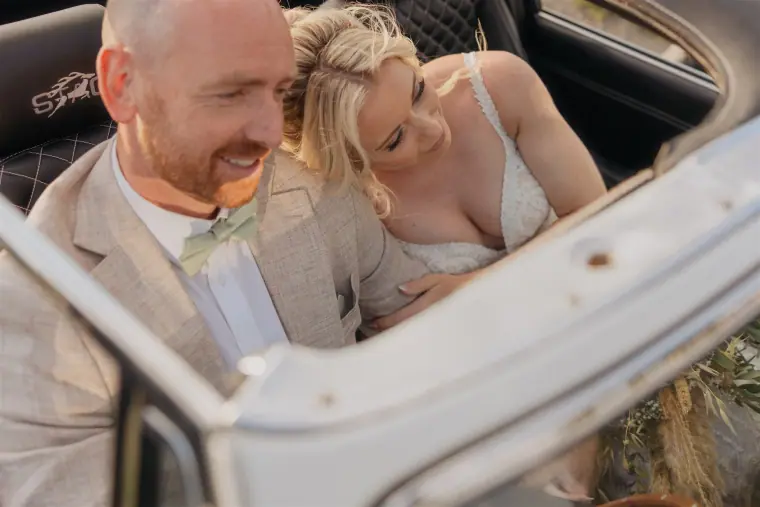 Sarah and Ben laughing together in the vintage convertible