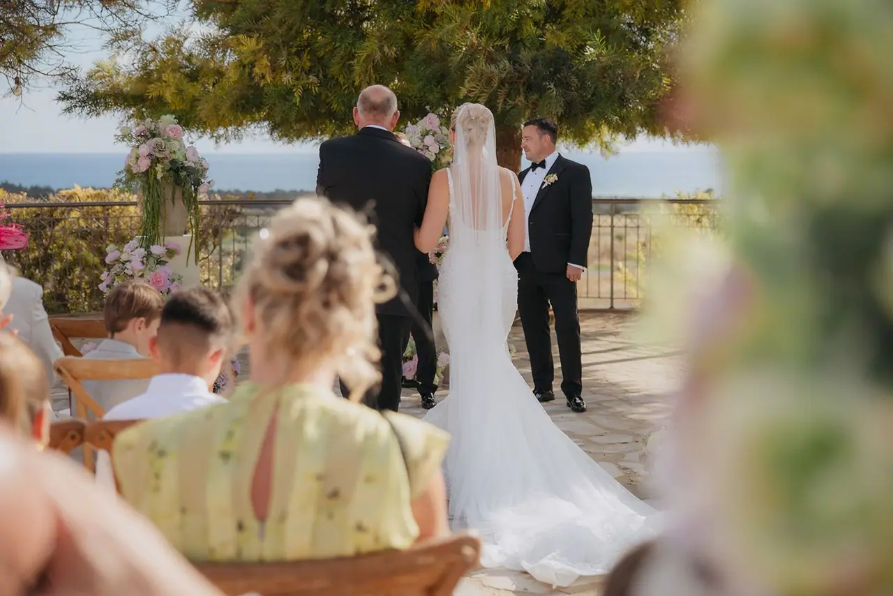 Zoe and her dad arriving at the front of the aisle, the sea behind Oliver