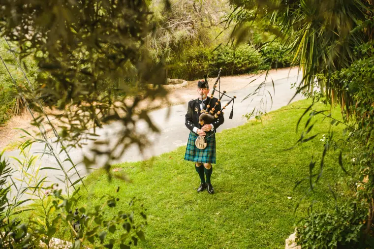 Bagpiper in tartan leading the procession across the lawn at Vasilias Nikoklis Inn