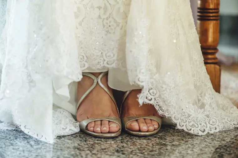 Close-up of Ruby's silver sandals beneath the lace hem of her gown