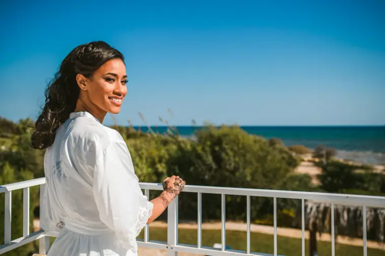 Raya in a white robe on a balcony overlooking the sea at Thalassines Beach Villas, Ayia Napa