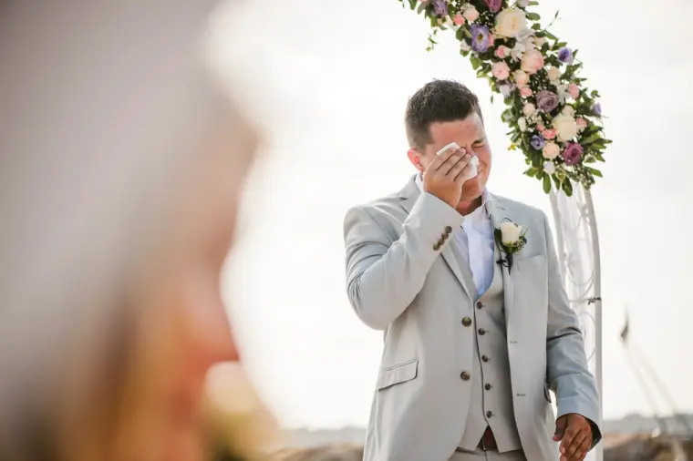 Nathan wiping away a tear at the flower-covered arch as Charlotte arrives