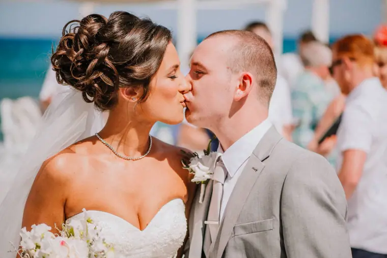 Louise and Mike kissing as guests mingle after the ceremony