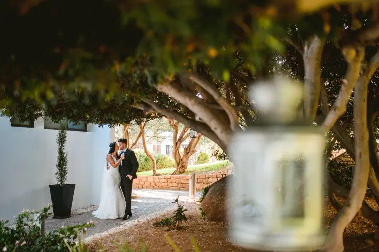Jaclyn and Steven on a garden path, framed by a hanging lantern and overhanging trees